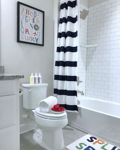 a white toilet sitting in a bathroom next to a bath tub and shower curtain with black and white stripes on it