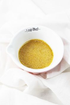 a white bowl filled with yellow liquid on top of a white cloth covered tablecloth