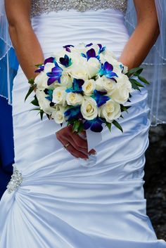 a bride holding a bouquet of white and blue flowers