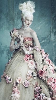 a woman in a white dress with flowers on it's chest and headdress