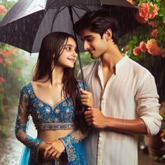 a man and woman standing under an umbrella in the rain with pink flowers behind them