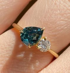 a woman's hand holding a ring with a blue and white diamond