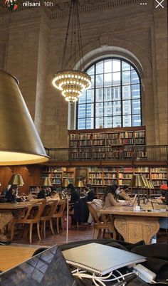 a large library filled with lots of books and people sitting at tables next to each other