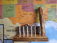 stacks of metal cups sitting on top of a wooden shelf in front of a map