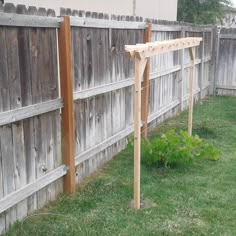 a wooden trellis in the grass next to a fence