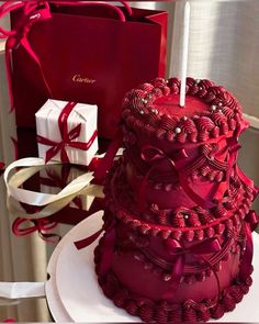 a red cake sitting on top of a white plate next to a box with a candle in it