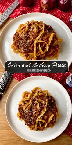 two white plates topped with pasta and sauce next to onions on a red table cloth