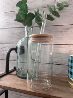 there is a glass jar with a straw in it next to a candle and potted plant