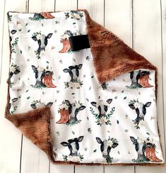 a blanket with deers and leaves on it sitting on a wooden floor next to a black tag