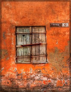 an orange wall with a window and street sign