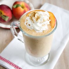 there is a drink with whipped cream in it on the table next to some apples