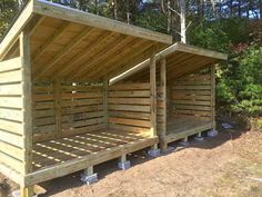 two wooden beds sitting next to each other on top of a dirt field with trees in the background