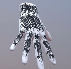 a hand with black and white designs painted on it's palm is held up in the air