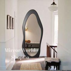 a large mirror in the middle of a hallway next to a chair and table with a lamp on it