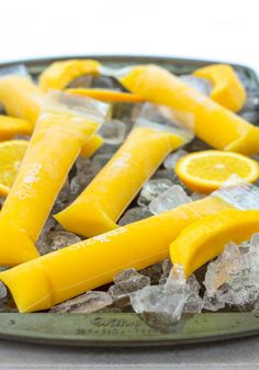 oranges and lemon peels are on ice in a glass dish with crushed ice