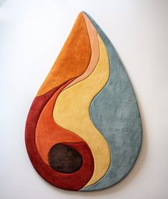 a painting on the wall with an orange and blue tear shaped piece in it's center