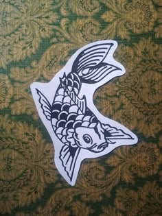 a fish sticker sitting on top of a green and gold wallpaper covered floor