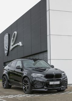 a black car parked in front of a building with a bmw logo on it's side