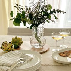 the table is set with plates, silverware and flowers in a vase on it