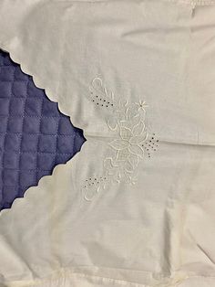 an embroidered piece of cloth on top of a quilted pillow case with white stitching