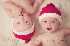 two babies wearing santa hats laying next to each other