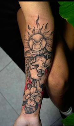 a woman's arm with flowers and sun tattoo on her left forearm, in black and white