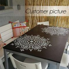 a table with white chairs around it in front of a wall that has a brown and white design on it