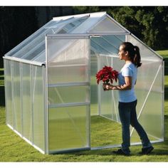 a woman standing in front of a green house holding a bouquet of flowers and looking at it