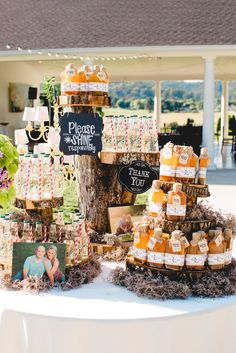 a table topped with lots of bottles of liquid next to a tree and sign that says please wine