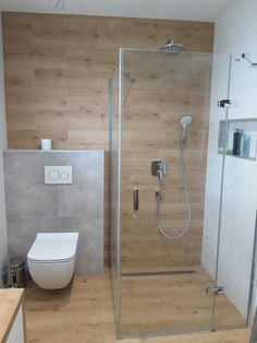 a bathroom with a toilet, shower and wooden floored walls in it's corner