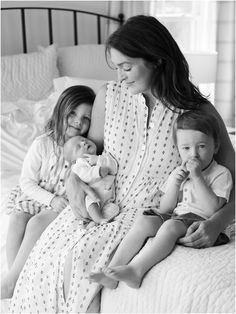 a woman and two children are sitting on a bed with their arms around each other