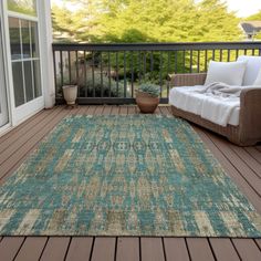 an outdoor area rug on a deck next to a couch and chair with pillows in front of it