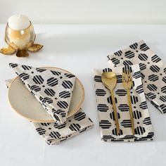 black and white place setting with gold cutlery, napkins and cups on table