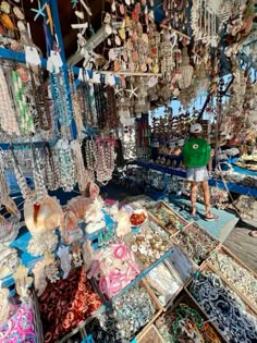 a man standing in front of a store filled with lots of necklaces