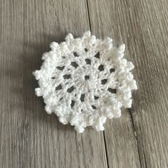 a white crocheted doily sitting on top of a wooden floor