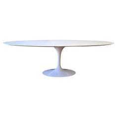 an oval dining table with white top and round base, in the shape of a tulip