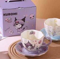 two cups and saucers sitting on a wooden tray next to a box with the word kuromi printed on it