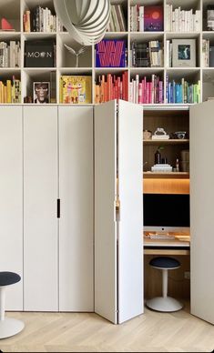 a room with white cabinets and bookshelves filled with books