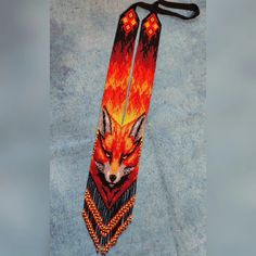 an orange and red tie with a fox on it's side, hanging from a black cord