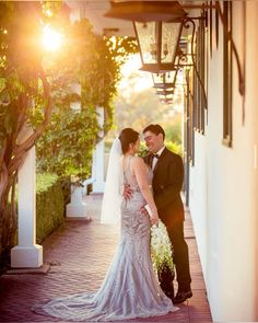 the bride and groom are posing for a photo together outside their home at sunset time