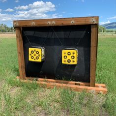 two yellow and black arrows are on the back of a wooden box in a grassy field