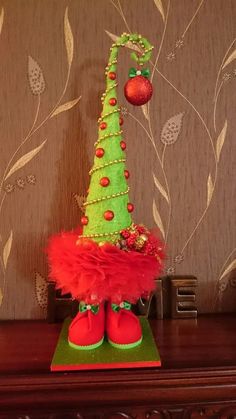 a small christmas tree with red and green decorations on it's head, sitting on top of a wooden table