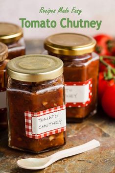 three jars filled with tomato sauce on top of a table next to tomatoes and a spoon