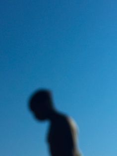 a blurry image of a man flying a kite in the sky with no clouds