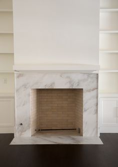 an empty fireplace in a room with white walls