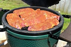 a close up of an open grill with meat on the outside and grass in the background