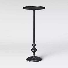 a black metal table with two candles on it's legs and one candle holder in the middle