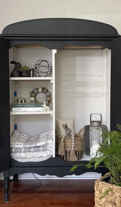 a black cabinet with books and plants in it