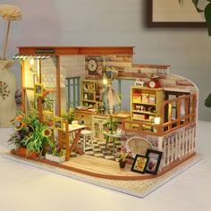 a doll house with furniture and decorations on the table next to a potted plant