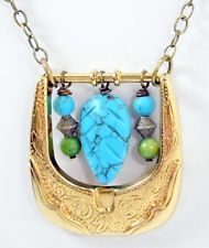 a gold necklace with blue and green beads hanging from it's center, on a white background